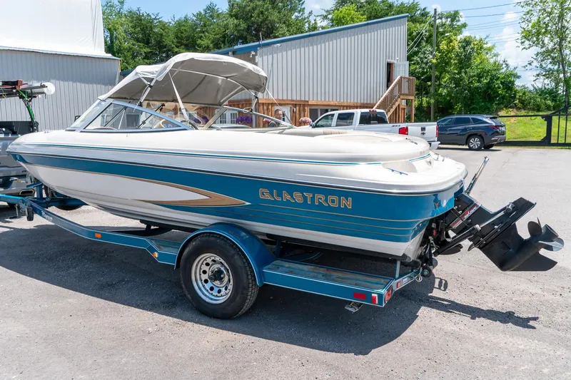 Slide: The Image of 1995 Glastron 195 SSV boat on trailer, parked outdoors near buildings and vehicles. - 8