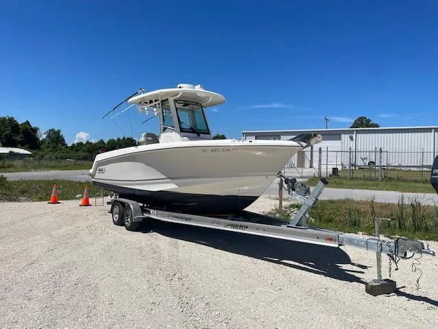 The Image of 2022 Boston Whaler 25' Outrage boat on trailer, parked outdoors under clear blue sky. - 0