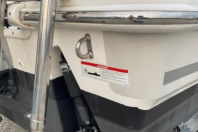 Slide: The Image of 2022 Boston Whaler 25' Outrage boat stern with safety warning label and metal fittings. - 11