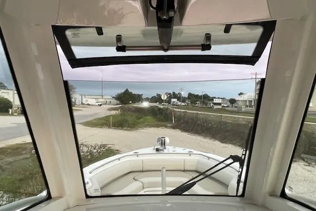 Slide: The Image of 2022 Boston Whaler 25' Outrage boat interior view through windshield, parked near coastal area. - 17