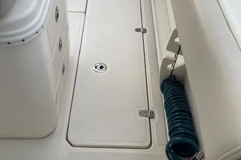 Slide: The Image of 2022 Boston Whaler 25' Outrage boat interior with storage compartment and coiled hose. - 28