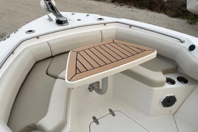 Slide: The Image of 2022 Boston Whaler 25' Outrage boat interior with cushioned seating and wooden table. - 29