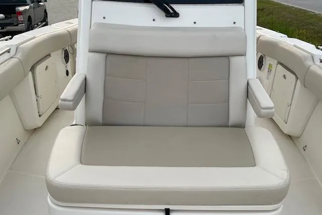 Slide: The Image of 2022 Boston Whaler 25' Outrage boat seating area with cushioned bench and armrests. - 32