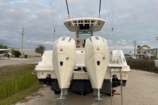 Slide: The Image of 2022 Boston Whaler 25' Outrage with dual outboard engines, parked on a gravel road. - 6