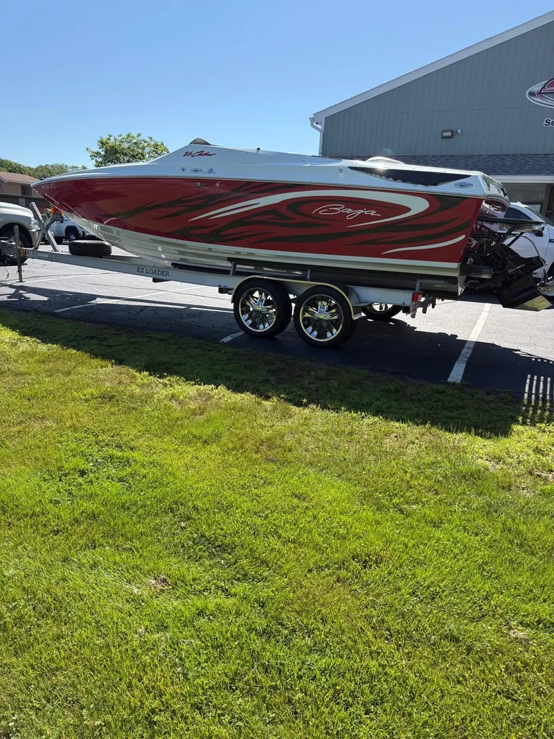 Slide: The Image of 2007 Baja 26 Outlaw speedboat on trailer, red and white design, parked outdoors. - 13