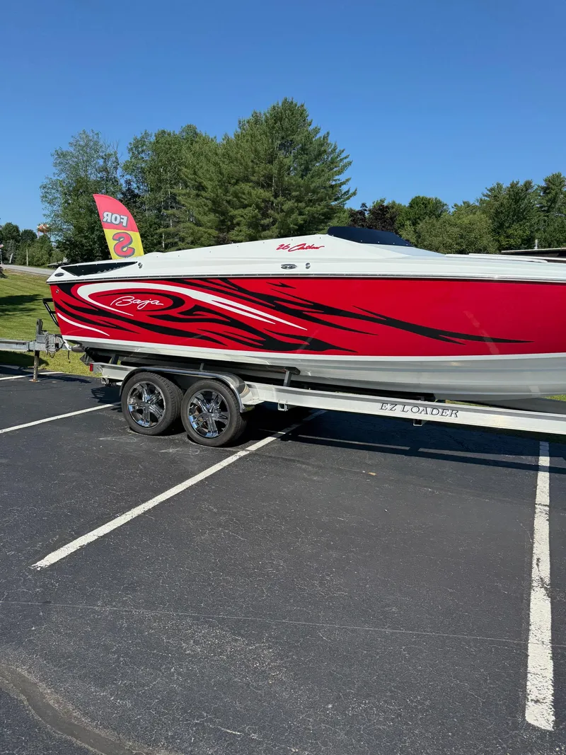 Slide: The Image of 2007 Baja 26 Outlaw boat with red and black design on trailer in parking lot. - 9