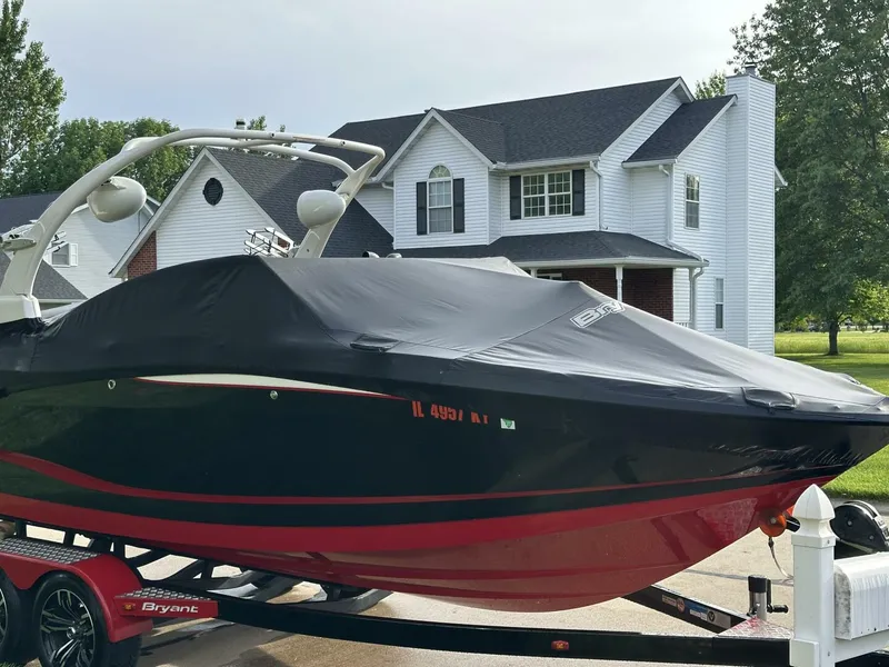 Slide: The Image of 2018 Bryant Calandra 23 boat covered, parked on trailer in front of a house. - 10