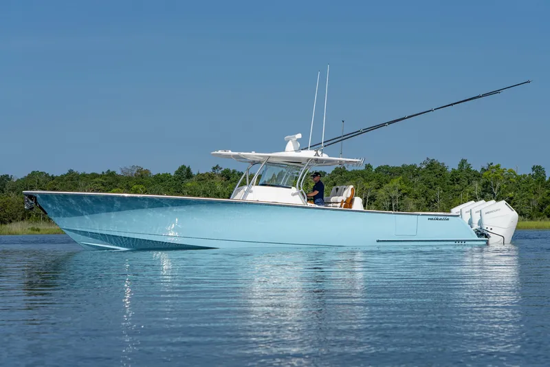 Slide: The Image of 2025 Valhalla Boatworks V-41 in blue, cruising on calm water with lush greenery in the background. - 14