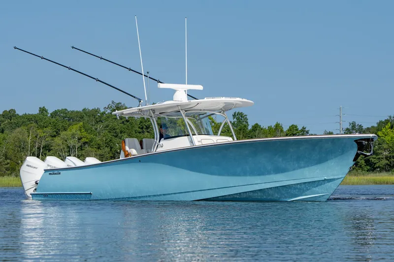 Slide: The Image of 2025 Valhalla Boatworks V-41 in blue, cruising on calm water with trees in background. - 3