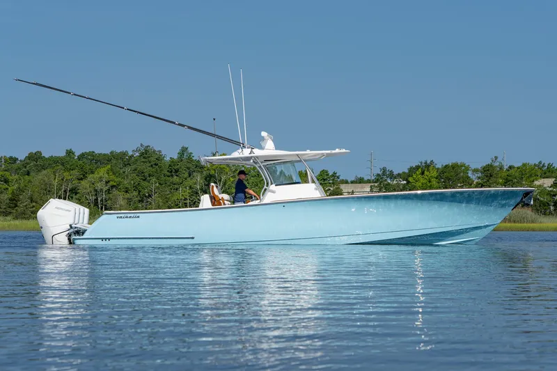 Slide: The Image of 2025 Valhalla Boatworks V-41 in blue, cruising on calm water with lush greenery background. - 7