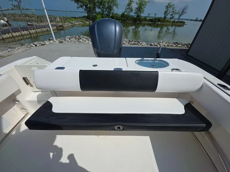 Slide: The Image of 2021 Robalo R242 Center Console boat interior with seating and sink, near a scenic waterfront. - 15