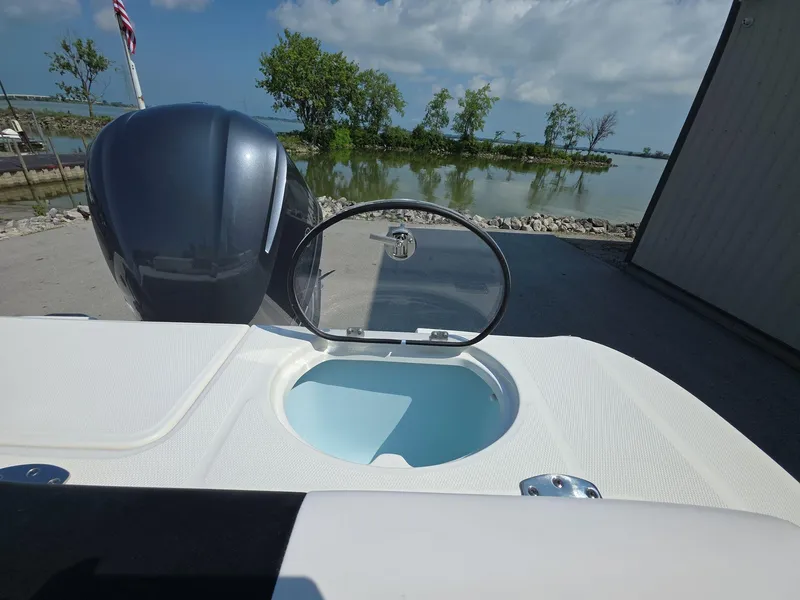 Slide: The Image of 2021 Robalo R242 Center Console boat with open hatch, near water and trees. - 16