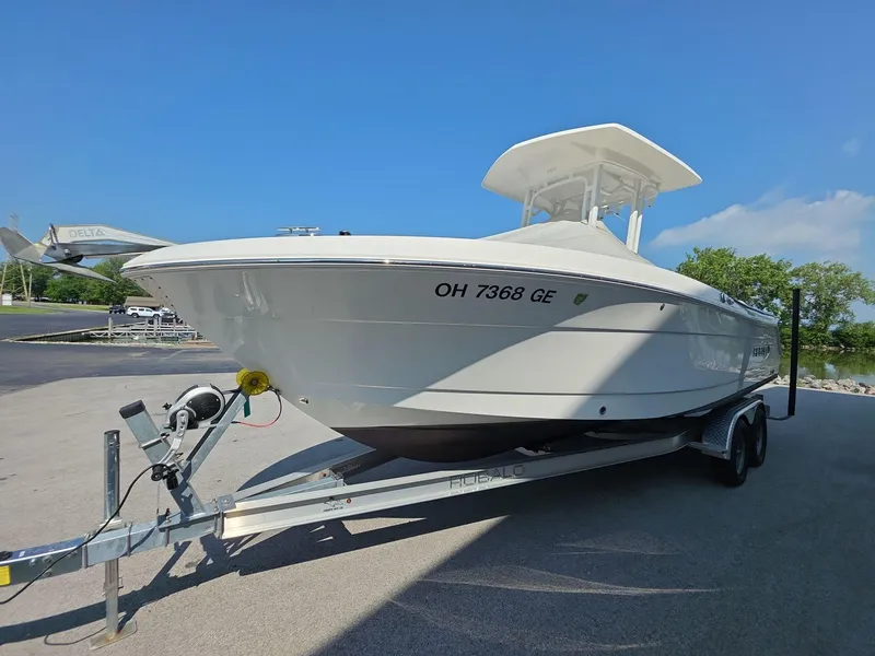 Slide: The Image of 2021 Robalo R242 Center Console boat on trailer, parked outdoors under clear blue sky. - 3