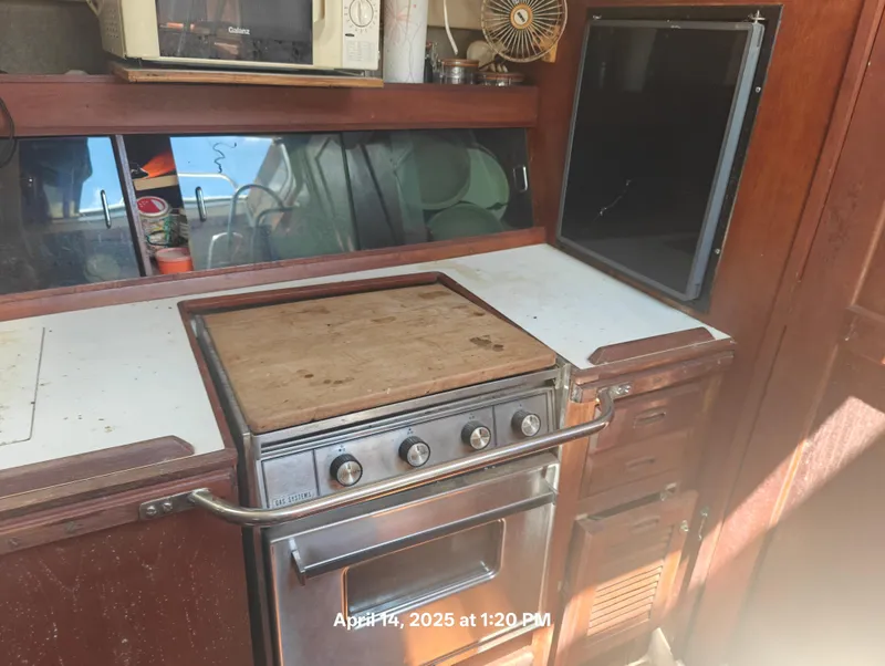 Slide: The Image of 1984 Hunter 40 yacht kitchen with stove, microwave, and wooden cabinetry. - 16