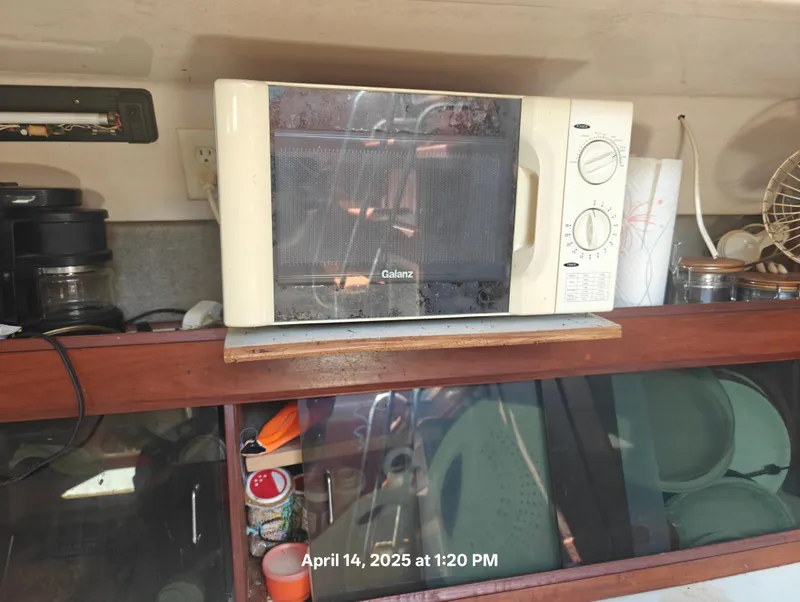 Slide: The Image of Microwave on a wooden shelf inside a 1984 Hunter 40 boat kitchen. - 17