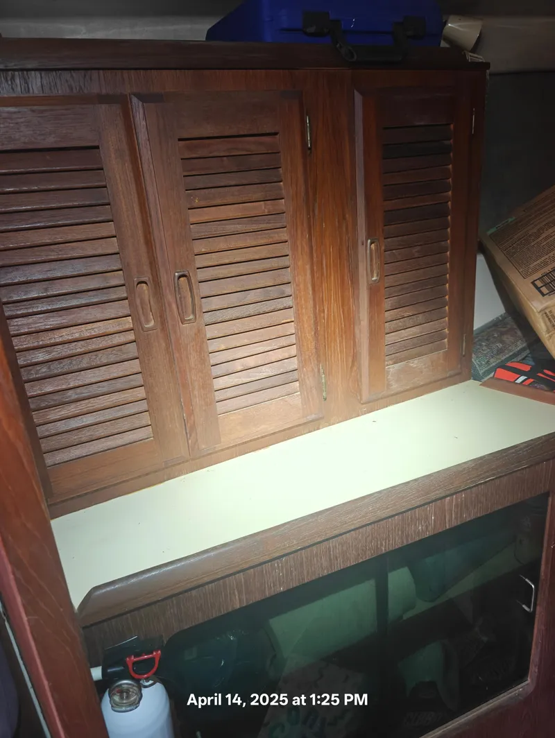 Slide: The Image of Wooden cabinet inside 1984 Hunter 40 boat, featuring louvered doors and countertop. - 29