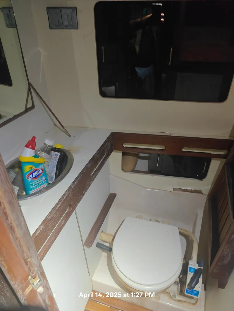 Slide: The Image of 1984 Hunter 40 boat bathroom with sink, cleaning supplies, and toilet. - 32