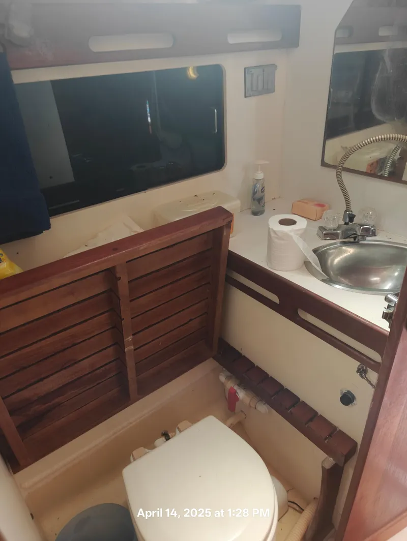 Slide: The Image of Compact bathroom in 1984 Hunter 40 sailboat with sink, toilet, and wooden accents. - 35