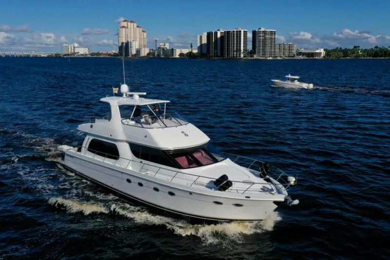 Slide: The Image of 2006 Carver 56 Voyager yacht cruising on blue water near city skyline. - 2