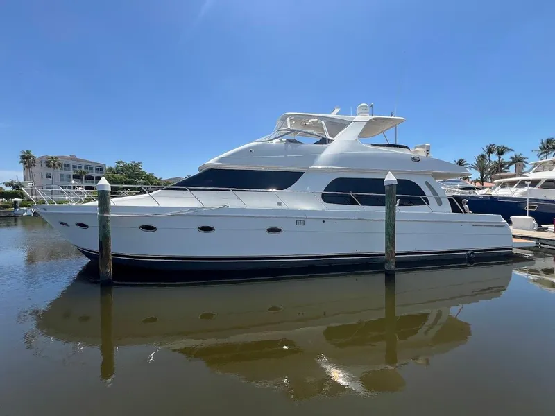 Slide: The Image of 2006 Carver 56 Voyager yacht docked in a marina under clear blue skies. - 4