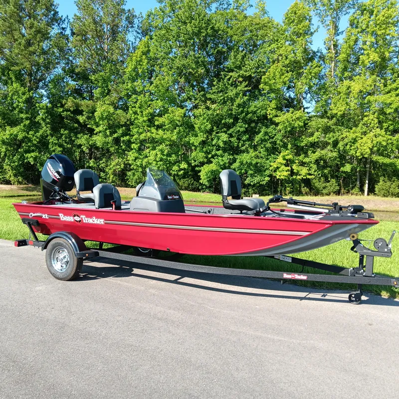 Slide: The Image of 2026 Tracker Bass Tracker Classic XL boat on trailer, parked on road with lush green trees. - 2