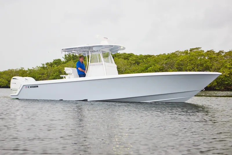Slide: The Image of 2026 Contender 32 ST boat on water, side view with lush greenery background. - 1