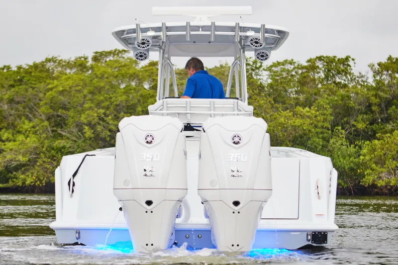 Slide: The Image of 2026 Contender 32 ST boat with dual engines, cruising on water, surrounded by greenery. - 2