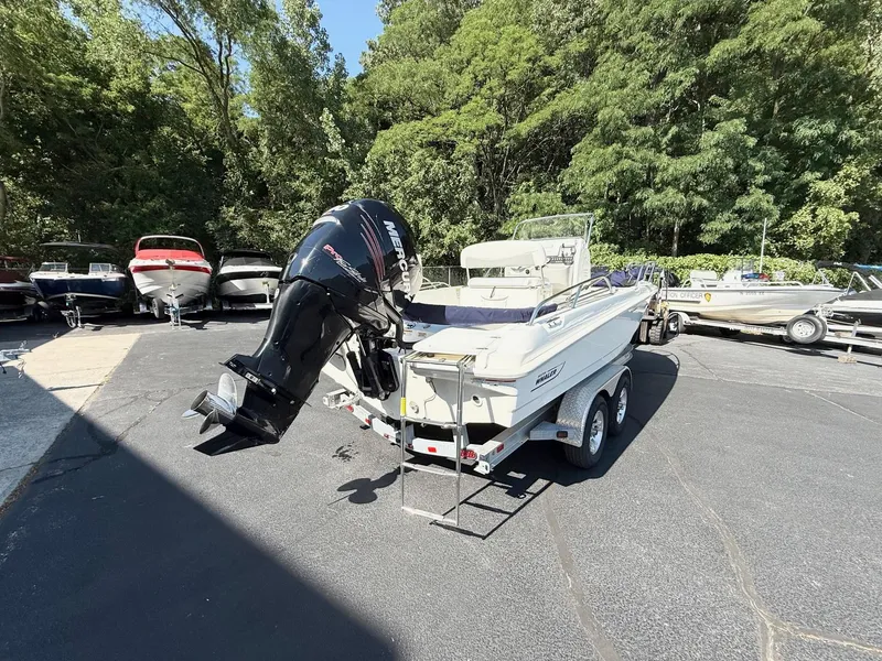 Slide: The Image of 2016 Boston Whaler 210 Dauntless boat on trailer, parked outdoors near trees. - 2