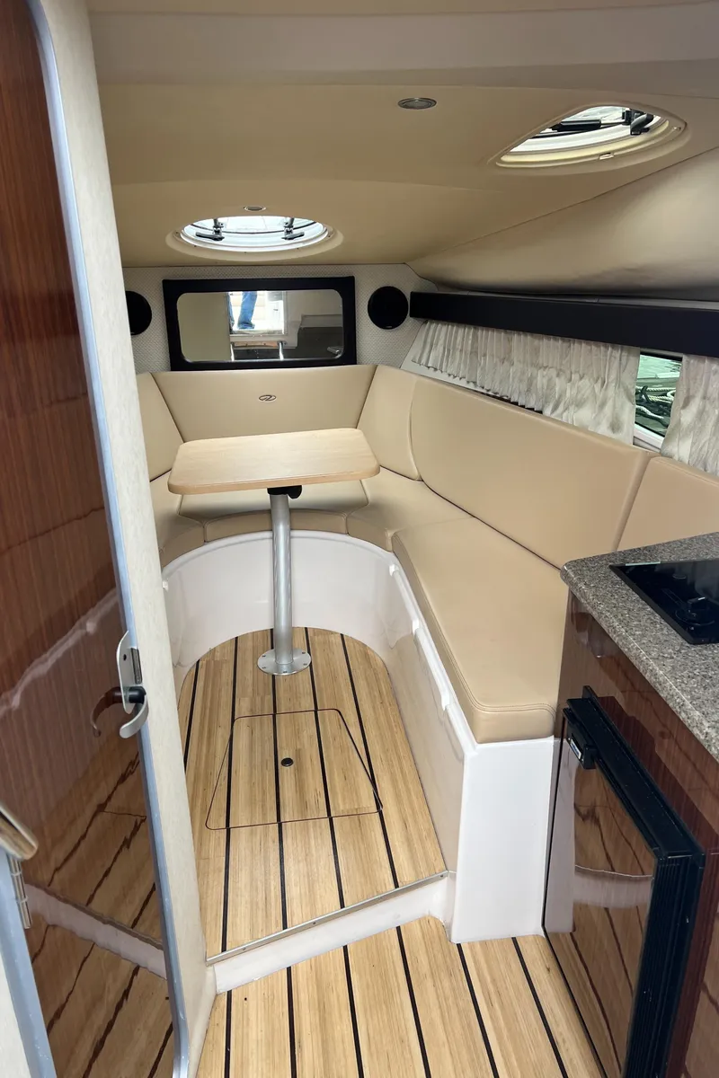 Slide: The Image of 2015 Regal 28 Express cabin interior with seating, table, and wood flooring. - 18