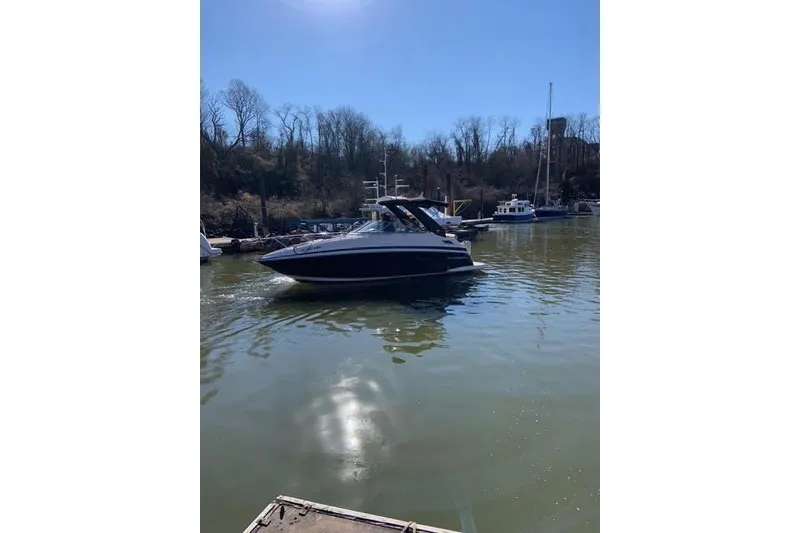 Slide: The Image of 2015 Regal 28 Express boat cruising on a calm river under clear blue skies. - 2