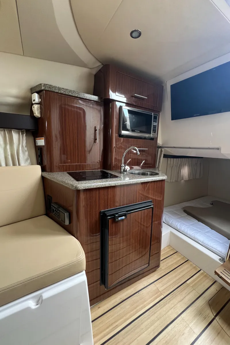 Slide: The Image of 2015 Regal 28 Express boat interior with kitchenette, microwave, and cozy sleeping area. - 20