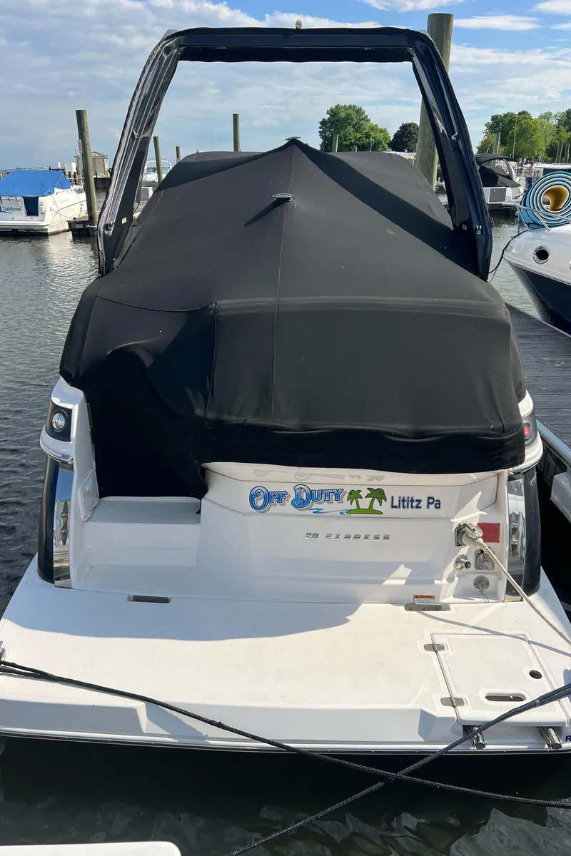 Slide: The Image of 2015 Regal 28 Express boat docked, covered with black tarp, in a marina setting. - 27