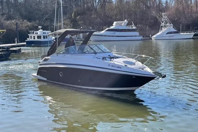 Slide: The Image of 2015 Regal 28 Express boat cruising on a calm river with other boats docked nearby. - 30