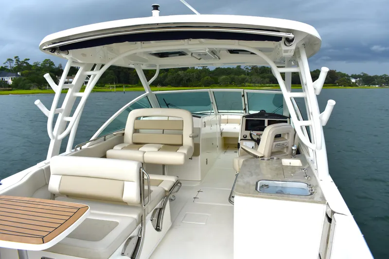 Slide: The Image of 2023 Boston Whaler 320 Vantage boat interior with seating and helm, on a calm lake. - 21