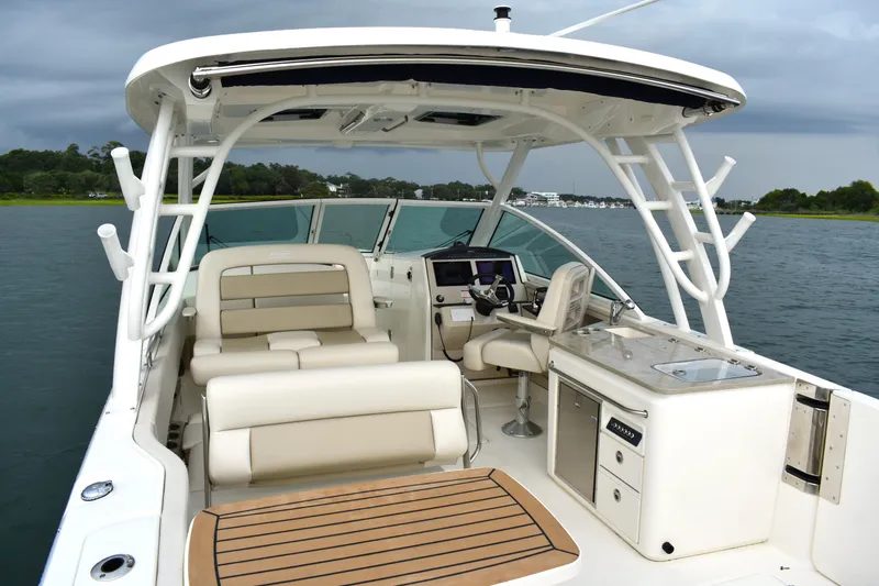 Slide: The Image of 2023 Boston Whaler 320 Vantage boat interior with seating and helm, on calm water. - 23