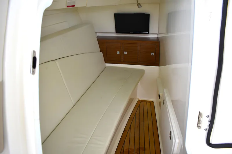 Slide: The Image of 2023 Boston Whaler 320 Vantage cabin interior with sofa, TV, and wooden cabinets. - 30