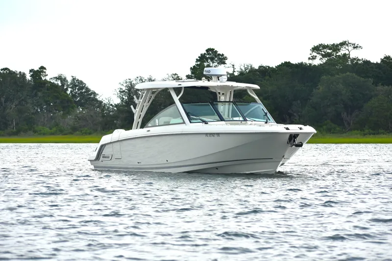 Slide: The Image of 2023 Boston Whaler 320 Vantage boat on calm water with lush green background. - 4