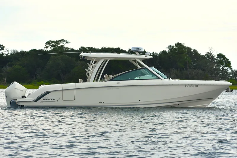 Slide: The Image of 2023 Boston Whaler 320 Vantage boat on water, side view with trees in background. - 5