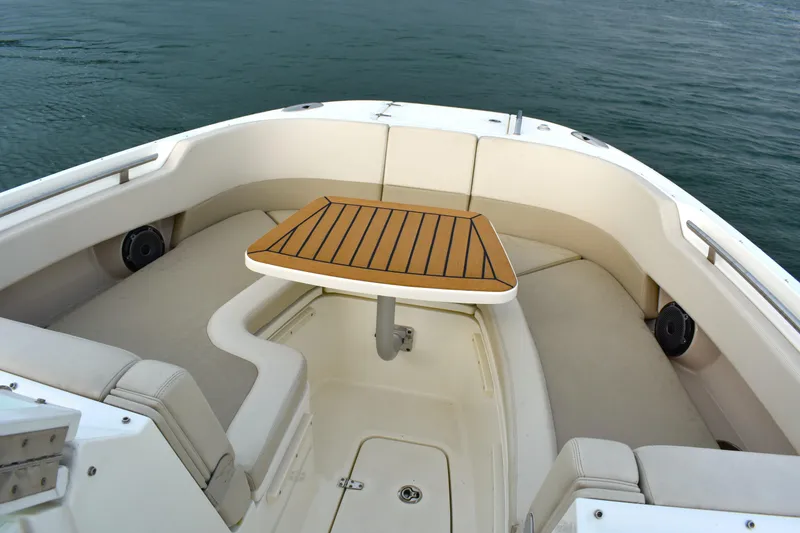 Slide: The Image of 2023 Boston Whaler 320 Vantage boat interior with cushioned seating and wooden table. - 8