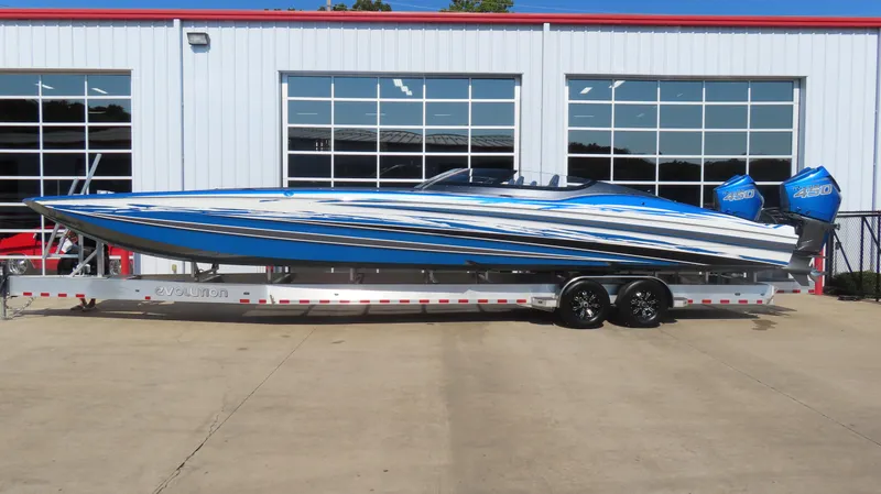Slide: The Image of 2023 MTI 390X speedboat on trailer, blue and white design, parked outside a garage. - 1