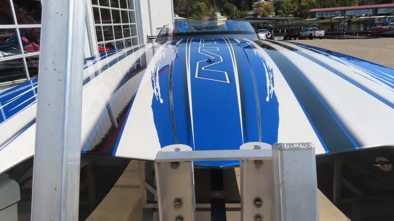 Slide: The Image of 2023 MTI 390X boat with blue and white stripes, docked at a marina. - 4