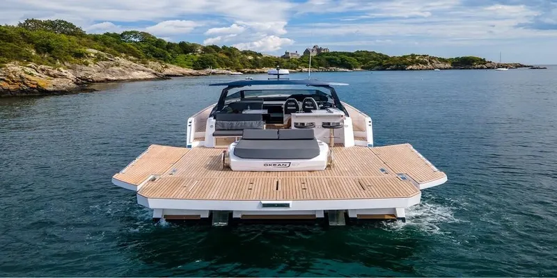 Slide: The Image of 2023 OKEAN 57 yacht cruising near a scenic coastline under a partly cloudy sky. - 0