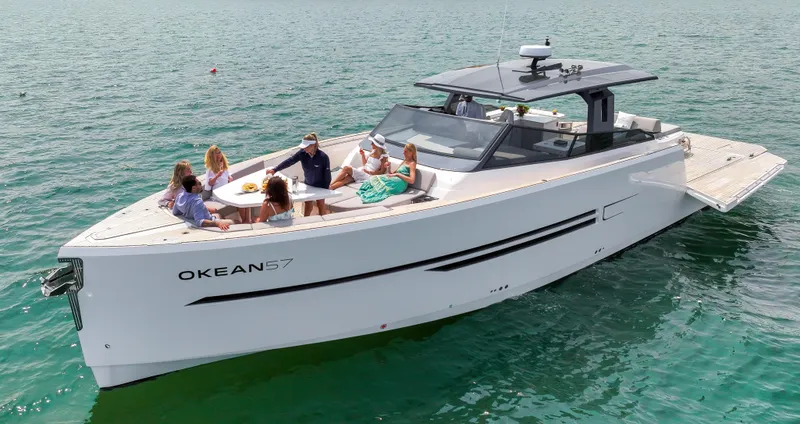 Slide: The Image of 2023 OKEAN 57 yacht with people relaxing on deck in open water. - 2