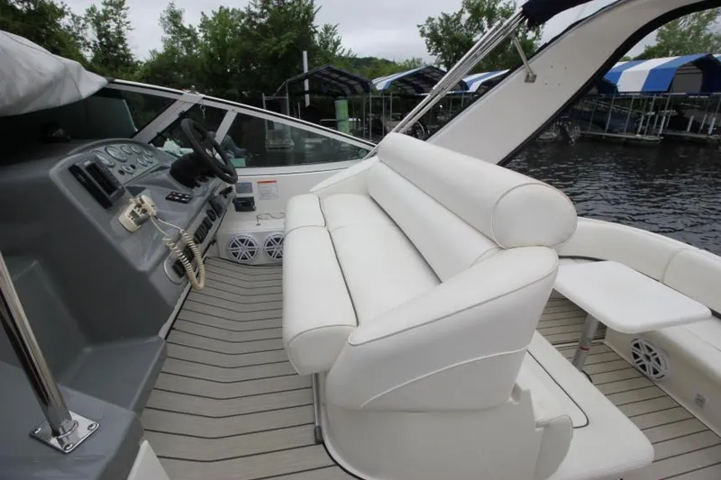 Slide: The Image of 2006 Cruisers Yachts 320 Express interior with white seating and helm, docked by water. - 12