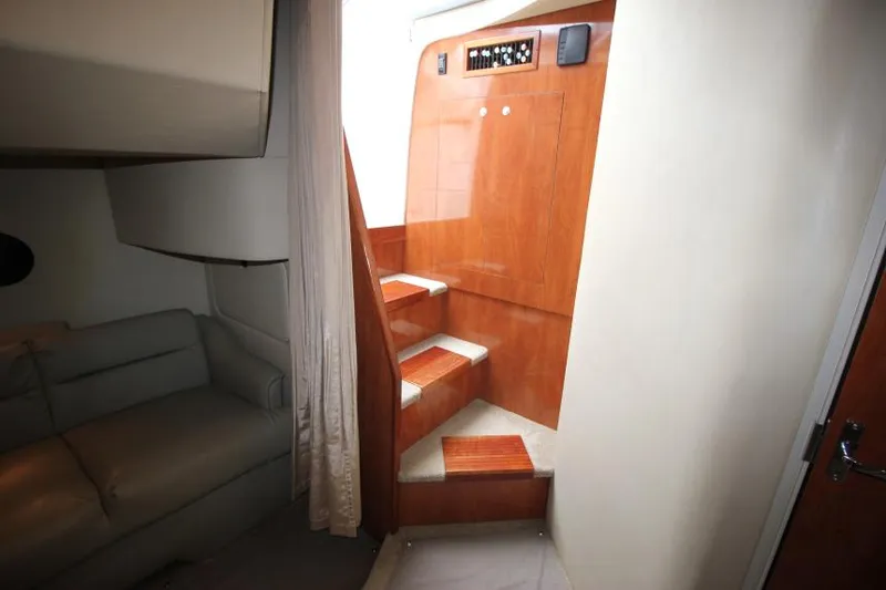 Slide: The Image of Interior of 2006 Cruisers Yachts 320 Express, featuring wooden stairs and a cozy seating area. - 18