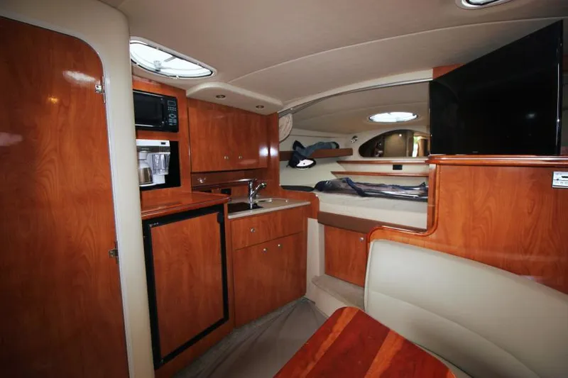 Slide: The Image of Interior of 2006 Cruisers Yachts 320 Express, featuring wood cabinetry, kitchenette, and seating area. - 19