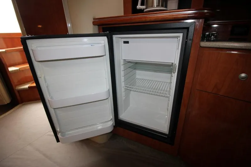 Slide: The Image of Open mini fridge inside 2006 Cruisers Yachts 320 Express, showcasing interior storage space. - 21