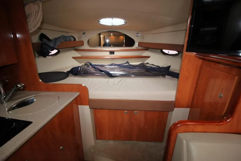 Slide: The Image of 2006 Cruisers Yachts 320 Express cabin interior with bed, sink, and wooden cabinetry. - 24