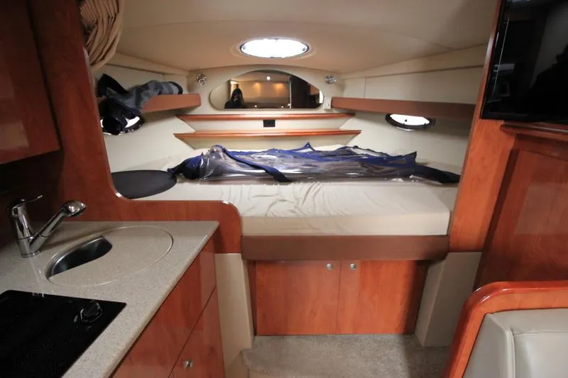 Slide: The Image of Interior of 2006 Cruisers Yachts 320 Express, featuring a cozy cabin with bed and kitchenette. - 26