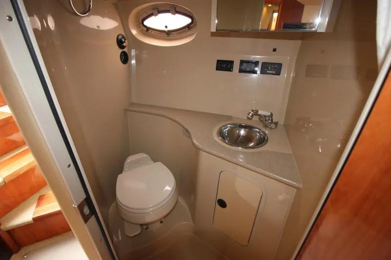 Slide: The Image of 2006 Cruisers Yachts 320 Express bathroom with sink, toilet, and porthole window. - 29